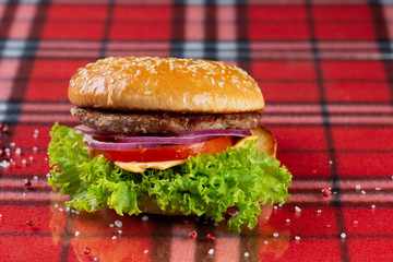  pork burger with cheese, tomatoes, cucumber, onions. bun with sesame seeds and bacon