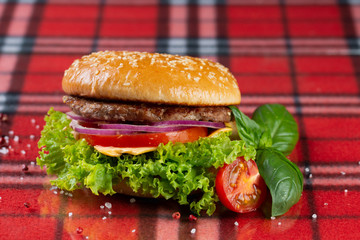  pork burger with cheese, tomatoes, cucumber, onions. bun with sesame seeds and bacon