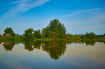 Peaceful rural summer european landscape with green trees and water