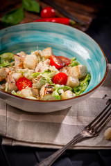 Caesar salad in a bowl with fried chicken, Parmesan cheese, croutons and lettuce, rustic style