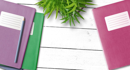 directly above shot of notebook or exercise book with blank adhesive label and pencil on desk with...
