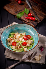 Caesar salad in a bowl with fried chicken, Parmesan cheese, croutons and lettuce, rustic style