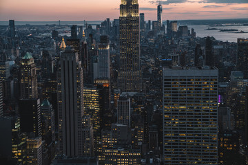 Aerial view of skyscrapers and towers in midtown skyline of Manhattan with evening sunset sky. Scenery cityscape of financial district with famous New York Landmark, illuminated Empire State Building