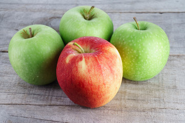 Red apple standing out from group of green apples