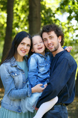 Obraz premium Family life. Portrait of parents and their daughter on the background of nature.
