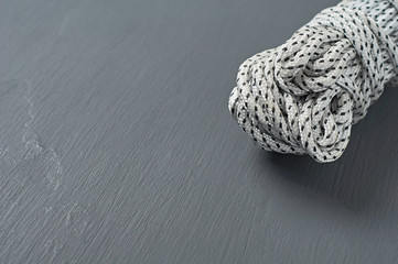 Bundle of black and white strong rope lies on dark concrete desk. Space for text