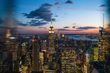 Aerial view of skyscrapers and towers in midtown skyline of Manhattan with evening sunset sky. Scenery cityscape of financial district with famous New York Landmark, illuminated Empire State Building