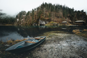 Rainy lake landscape with boat and reflection of the forest