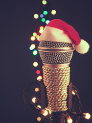 Close up of a microphone with the hat of Santa and blurred lights background