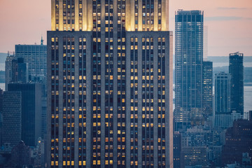 Aerial view of skyscraper building with lighted windows located in New York city at evening time. Night life of metropolis, offices and real estate. Downtown structure