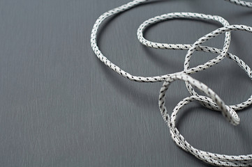 Scattered black and white strong rope lies on dark concrete desk. Space for text