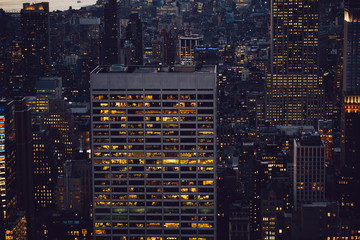 Fototapeta na wymiar Aerial view of various high Manhattan skyscrapers buildings with lighted windows located in New York city at evening time. Night life of metropolis, offices and real estate. Downtown structures