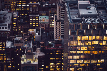 Aerial view of skyscraper building with lighted windows located in New York city at evening time. Night life of metropolis, offices and real estate. Downtown structure