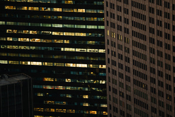 Aerial view of various high Manhattan skyscrapers buildings with lighted windows located in New York city at evening time. Night life of metropolis, offices and real estate. Downtown structures