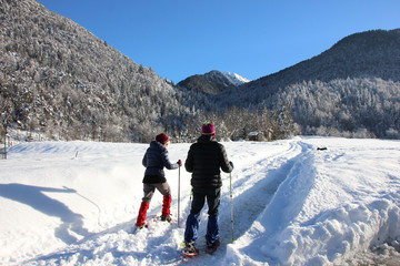Fototapeta na wymiar Snowshoe walkers running in powder snow in Trentino, Italy. Outdoor winter activity in the Alps.
