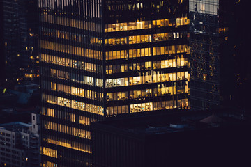 Obraz na płótnie Canvas Aerial view of various high Manhattan skyscrapers buildings with lighted windows located in New York city at evening time. Night life of metropolis, offices and real estate. Downtown structures
