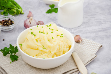 Mashed potatoes with butter, milk, garlic and green onions in a bowl on a gray background. A traditional dish of Ukrainian, Russian cuisine.
