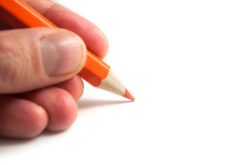 Closeup of orange pencil color in hand on white background
