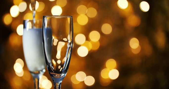 Champagne is poured into glasses against the background of New Year 's garland.