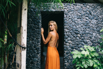 Attractive female in orange dress standing on doorway