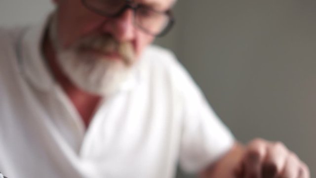 A gray mature man with glasses while working with a laptop. Happy old age, active pensioner, business concept