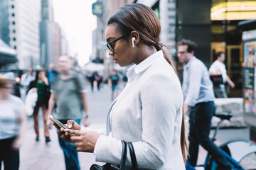 Busy ethnic female using smartphone on street