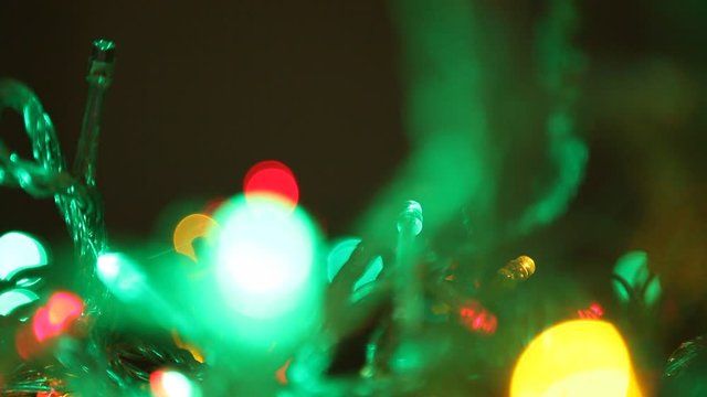 Green lights of New Year  garland blink close up. Bright green lights of a New Year's garland actively pulsate in a dark room. Then they freeze and gradually slowly fade. Defocused image