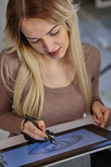 girl artist draws a digital pen on a professional tablet in her studio