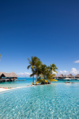 French Polynesia. Over water bungalows, sandy beach with palm trees and pool, Bora Bora