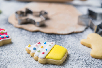 Close up of glazed christmas cookie on table with with ingredients and cooking equipment in the background
