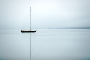 A black & white sail boat ancored in still waters