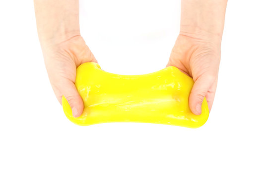 Modern toy called slime. Child playing transparent yellow slime. Hands holding a mucus isolated on a white background. Selective focus.