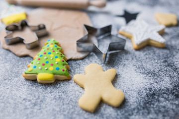 Fototapeta premium Making Christmas cookies concept made of sugar, cutters, dough, rolling pin and biscuits with colorful icing on table.
