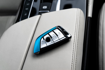 Closeup inside vehicle of wireless key ignition on white perforated leather seat. Wireless start...