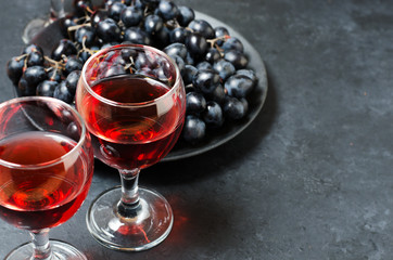 Red wine in glasses, a bunch of black grapes. Dark background. Copy space