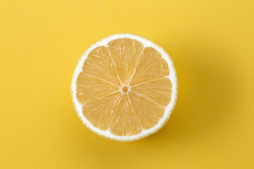 Macro photo of lemon fruit slice on yellow background.