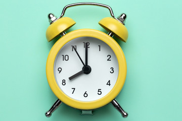 Yellow round alarm clock on the cyan background.