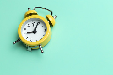 Yellow round alarm clock on the cyan background.