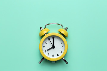Yellow round alarm clock on the cyan background.
