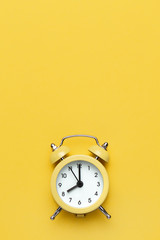 Yellow round alarm clock on the yellow background.