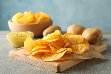 Potato chips. Beer snacks, sauce, potato on cutting board, on grey background, space for text. Closeup