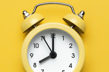 Yellow round alarm clock on the yellow background.