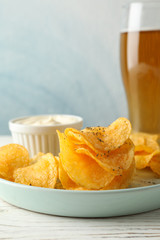Potato chips and glass of beer. Beer snacks, sauce on white wooden background, space for text. Closeup