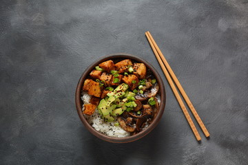 Sweet, spicy , crispy and fried Tofu in teriyaki sauce served in a bowl with avocado,fried mushrooms, sesame seeds and rice. Healthy vegan food, gluten-free