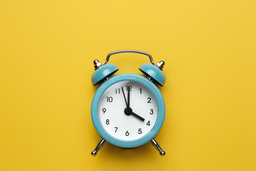 Blue round alarm clock on the cyan background.