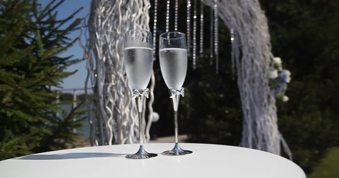 Beautifully set white table in the foreground with plates of cutlery glasses and decoration recorded with a smooth movement of the camera to the left