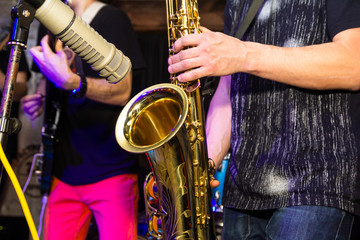 Obraz premium Musical instruments, hands holding saxophone. Musician playing saxophone.