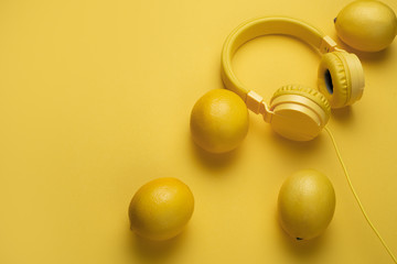 Yellow headphones decored with lemons on yellow background. Music concept.