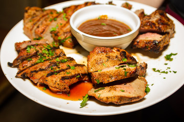 Grilled steak with sauce on a plate. Dish with a lot of fried meat.