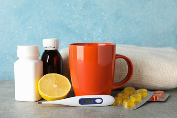 Medical bottles, pills, lemon and thermometer on grey table, space for text